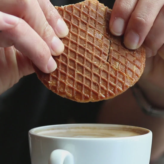 Video of a stroopwafel being broken in two above a cup of coffee, showing the caramel in the center.